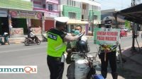 Tampak Anggota Satlantas Polres Oku Selatan Sedang Memasangkan Masker Kepada Salah seorang Pengendara Yang Abai tidak Memakai Masker Sementara Anggota Satu Nya Memegang Papan Banner Peringati Warga Pentingnya Masker (Foto Dok Satlantas Polres oku Selatan)